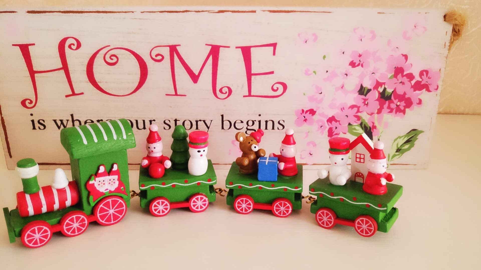 Decorative Christmas train set with Santa Claus figures on a wooden surface.